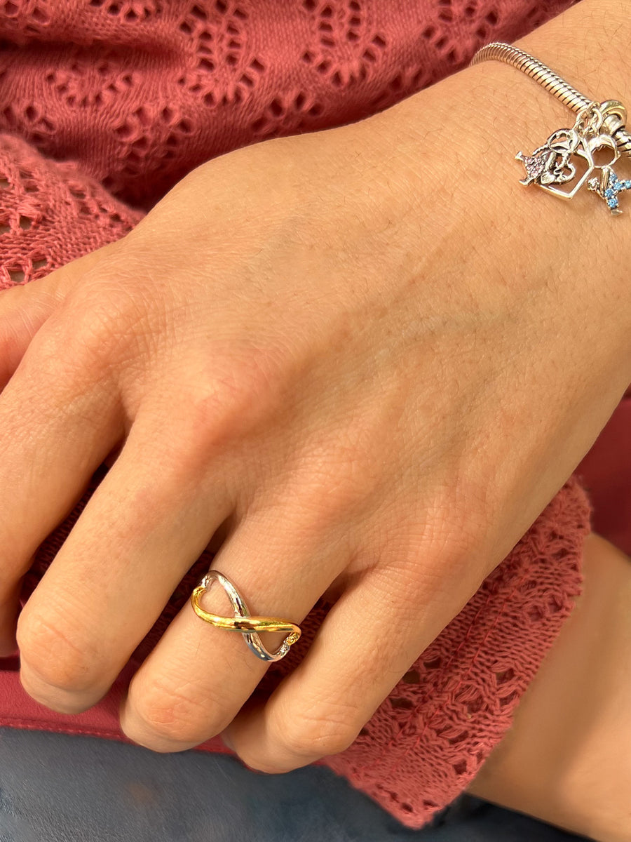 Anillo abierto que entrelaza dos corazones en forma de infinito que combina plata y oro.