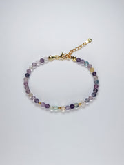 Pulsera hecha a mano con cuentas redondas facetadas de fluorita natural de 4 mm en tonos suaves y variados, y bolitas de 3 mm de plata de ley. Acabada en plata de ley 925 con baño de oro de 18k. 