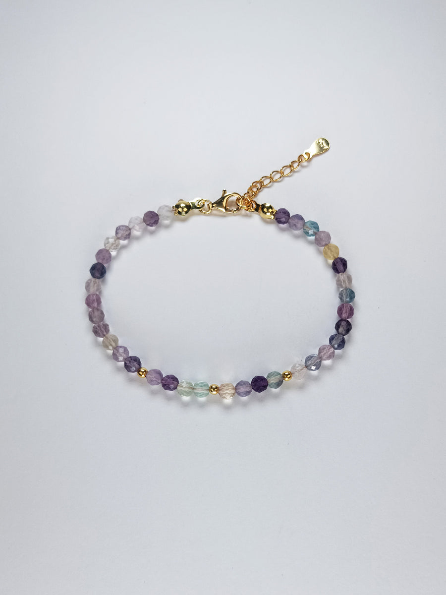 Pulsera hecha a mano con cuentas redondas facetadas de fluorita natural de 4 mm en tonos suaves y variados, y bolitas de 3 mm de plata de ley. Acabada en plata de ley 925 con baño de oro de 18k. 